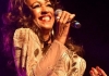 Sheila Ferguson singing into a microphone, wearing a gold dress. Sheila Ferguson singing into a microphone, wearing a gold dress.