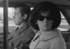 A man and a woman sitting in a car. The woman is looking out the window wearing sunglasses A man and a woman sitting in a car. The woman is looking out the window wearing sunglasses