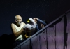 An old man wearing a white tank top interacting with the puppet of a duck An old man wearing a white tank top interacting with the puppet of a duck