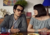 A man and woman sit at a kitchen table, looking at one another A man and woman sit at a kitchen table, looking at one another