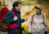 An old woman in outdoor gear looking at a young man with a red rucksack who is talking to her An old woman in outdoor gear looking at a young man with a red rucksack who is talking to her