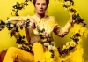 Comedian Jen Brister wearing yellow shirt, trousers and boots, surrounded by yellow roses against a yellow background Comedian Jen Brister wearing yellow shirt, trousers and boots, surrounded by yellow roses against a yellow background