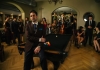 Pianist Scott Bradlee sitting on a pool table surrounded by other performers in vintage clothes Pianist Scott Bradlee sitting on a pool table surrounded by other performers in vintage clothes