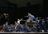 A man in a soldier uniform standing on a tank and leaning towards a woman dressed in white, both surrounded by other soldiers A man in a soldier uniform standing on a tank and leaning towards a woman dressed in white, both surrounded by other soldiers