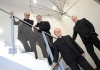 Four musicians from the Coull Quartet stand on a glass and chrome staircase, wearing black suits Four musicians from the Coull Quartet stand on a glass and chrome staircase, wearing black suits