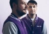 Two men in purple and grey football jackets against a neutral background Two men in purple and grey football jackets against a neutral background