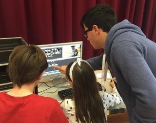 Two children work on editing a video, directed by a workshop leader. Two children work on editing a video, directed by a workshop leader.