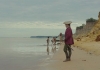 A man wearing a red officer's jackets and hat stands on a beach looking out to sea A man wearing a red officer's jackets and hat stands on a beach looking out to sea
