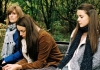 A woman and her two teenage daughters sit on a bench looking solemn A woman and her two teenage daughters sit on a bench looking solemn