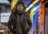A woman in a black leather jacket walks down a busy street with her hood up A woman in a black leather jacket walks down a busy street with her hood up