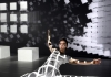 A dancer dressed in white surrounded by digital projections of white cubes against a black background A dancer dressed in white surrounded by digital projections of white cubes against a black background
