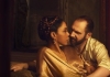 A white man and a black woman in gold clothes lounging in an embrace A white man and a black woman in gold clothes lounging in an embrace