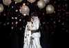A woman in a white kimono and a man in a white Navy uniform stand under lanterns and falling petals. A woman in a white kimono and a man in a white Navy uniform stand under lanterns and falling petals.