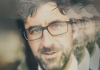 A closeup image of Mark Watson with reflected images behind him A closeup image of Mark Watson with reflected images behind him