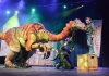A young boy smiles whilst petting the head of a realistic dinosaur puppet A young boy smiles whilst petting the head of a realistic dinosaur puppet