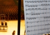 A sheet of music in focus against an out of focus view of the Butterworth Hall A sheet of music in focus against an out of focus view of the Butterworth Hall