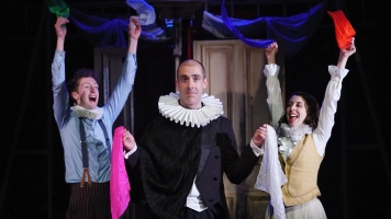 A man in a ruff stands with two other actors, one male and one female, holding coloured handkerchiefs A man in a ruff stands with two other actors, one male and one female, holding coloured handkerchiefs