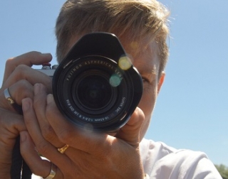 A woman with short blonde hair holds a dslr camera towards us A woman with short blonde hair holds a dslr camera towards us