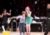 A woman in a green dress and a santas hat, and a young boy, are surrounded by bubbles on a stage A woman in a green dress and a santas hat, and a young boy, are surrounded by bubbles on a stage