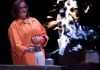 A woman in a white lab coat using a small flame thrower A woman in a white lab coat using a small flame thrower