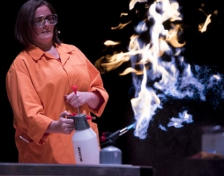 A woman in a white lab coat using a small flame thrower A woman in a white lab coat using a small flame thrower