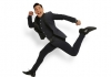 Comedian Russell Kane jumps through the air wearing a dark suit. Comedian Russell Kane jumps through the air wearing a dark suit.